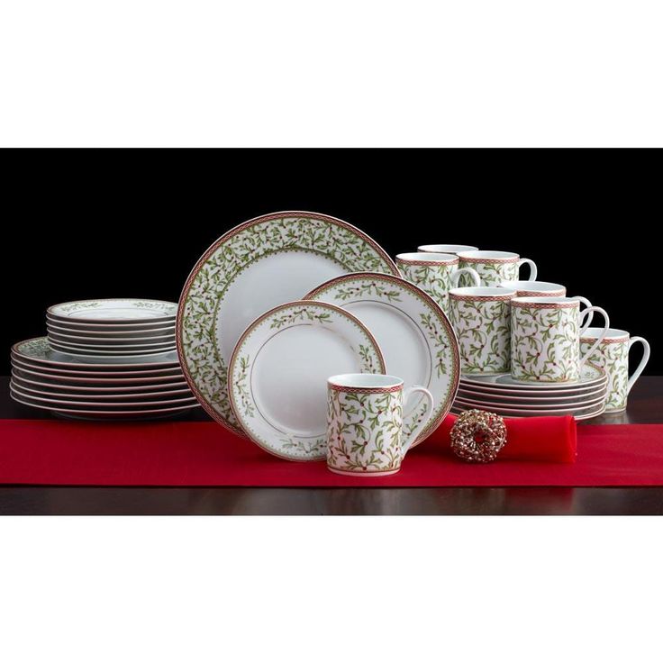 a table with plates and cups on top of red placemats in front of a black background