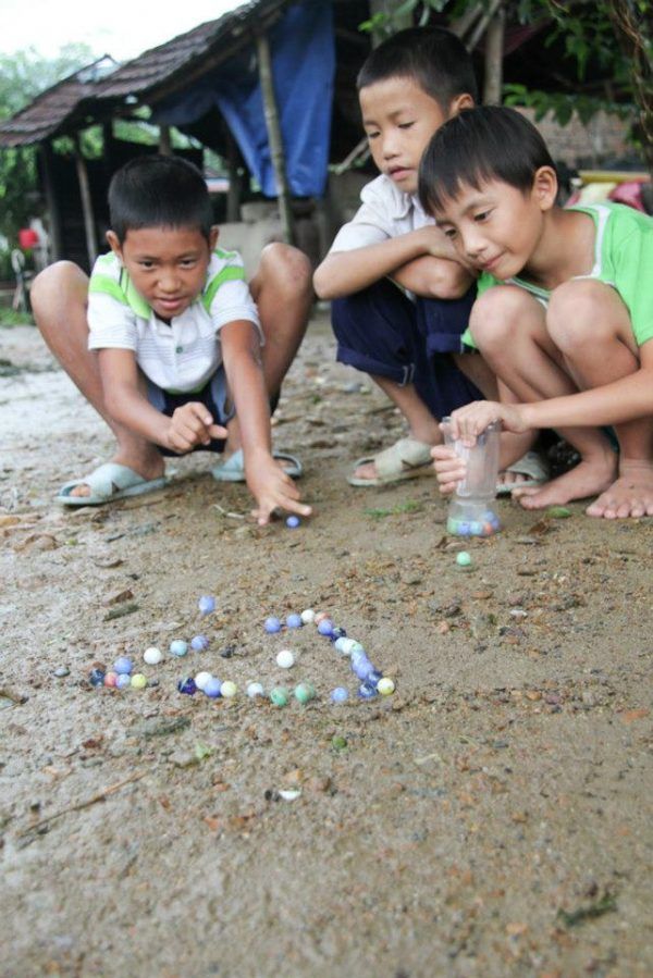 three children playing with beads on the ground