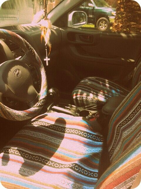 the interior of a car with a steering wheel and colorful blanket on the dash board