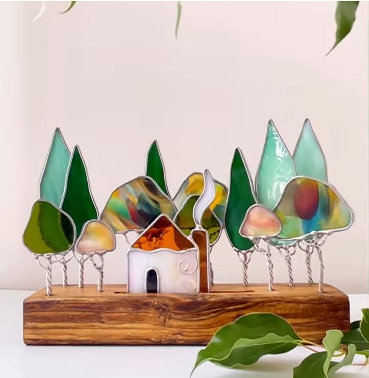 a group of glass trees sitting on top of a wooden stand next to a plant