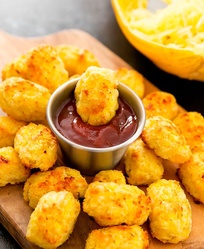 some fried food on a cutting board with ketchup in a small bowl next to it