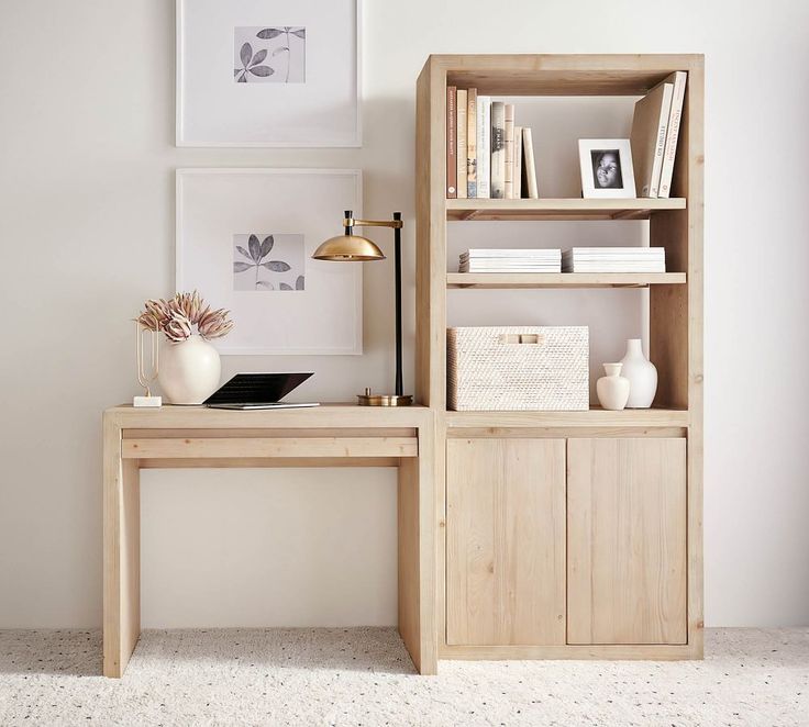 a wooden desk sitting next to a book shelf with books on top of it in front of a white wall