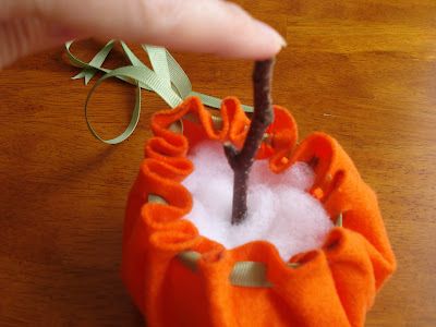 someone is holding an ornament made out of felt and cotton with a twig sticking out of it