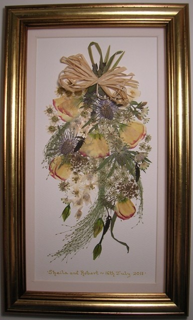 a painting hanging on the wall next to a wooden frame with flowers and leaves in it