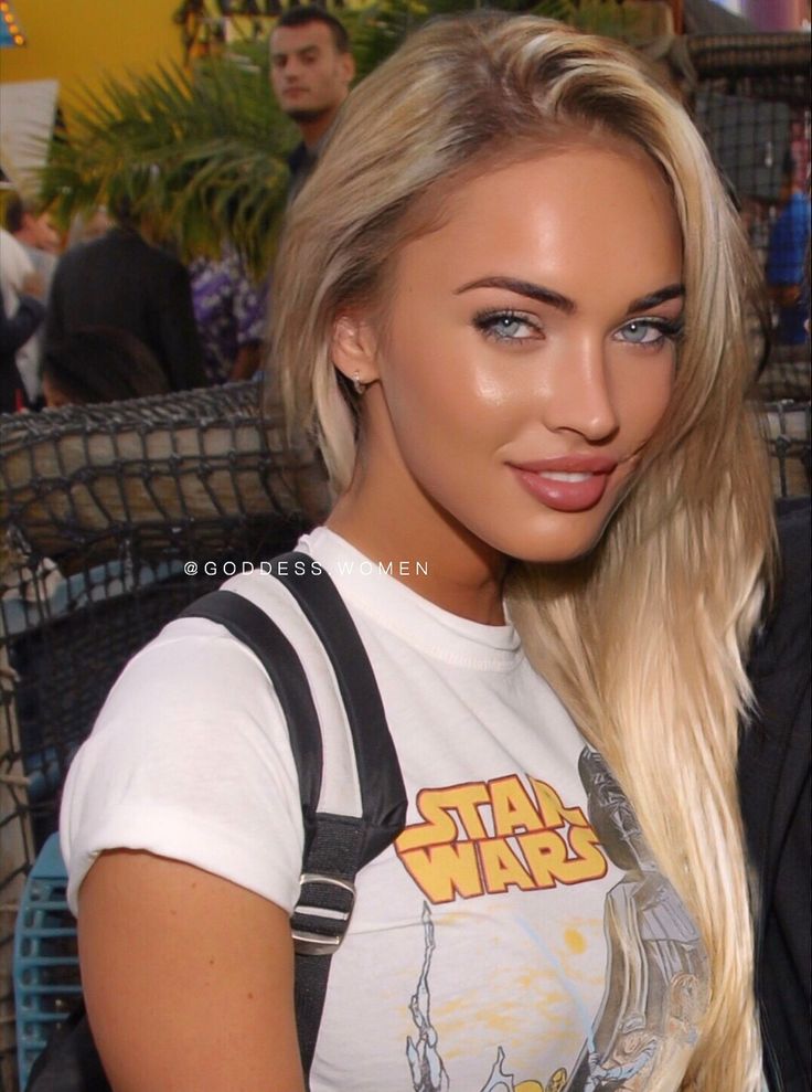 a woman with long blonde hair wearing a star wars t - shirt and suspenders