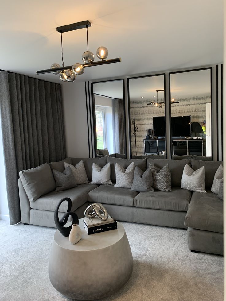 a living room filled with gray couches and pillows on top of carpeted flooring