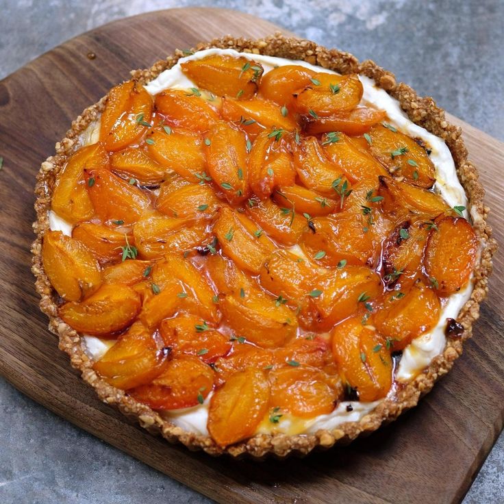 a tart topped with sliced oranges on top of a wooden cutting board