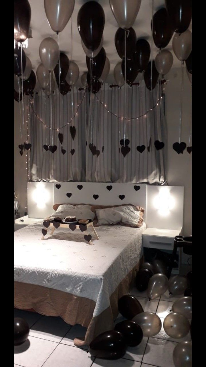 a bed with lots of balloons hanging from the ceiling