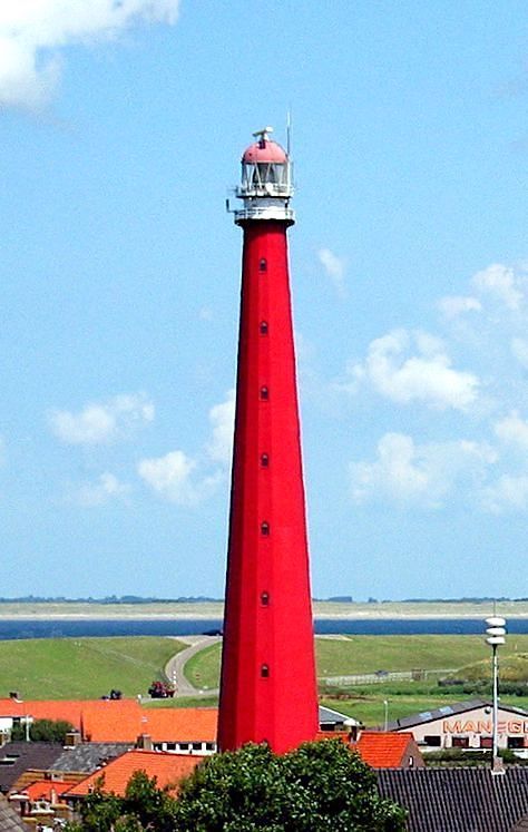 a red light house sitting on top of a lush green field