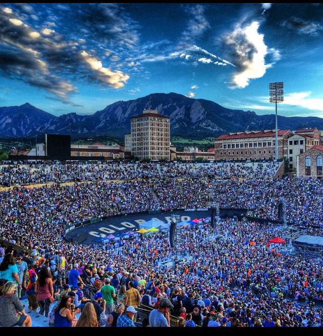 a large group of people are gathered in the stadium to watch a sporting event with mountains in the background