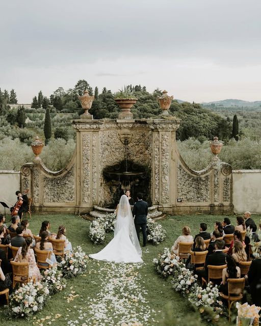 a bride and groom walking down the aisle at their wedding ceremony in front of an outdoor fireplace