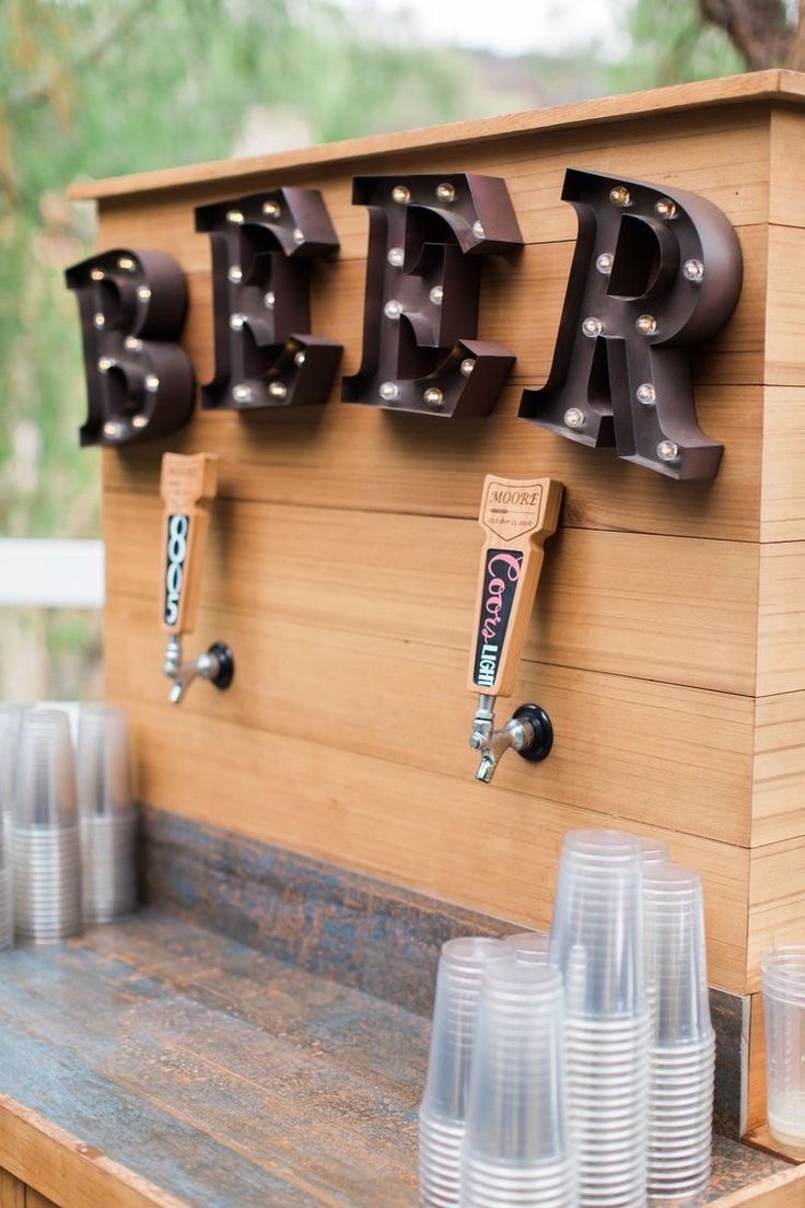 there are many cups on the table with beer written on it and hanging from the wall