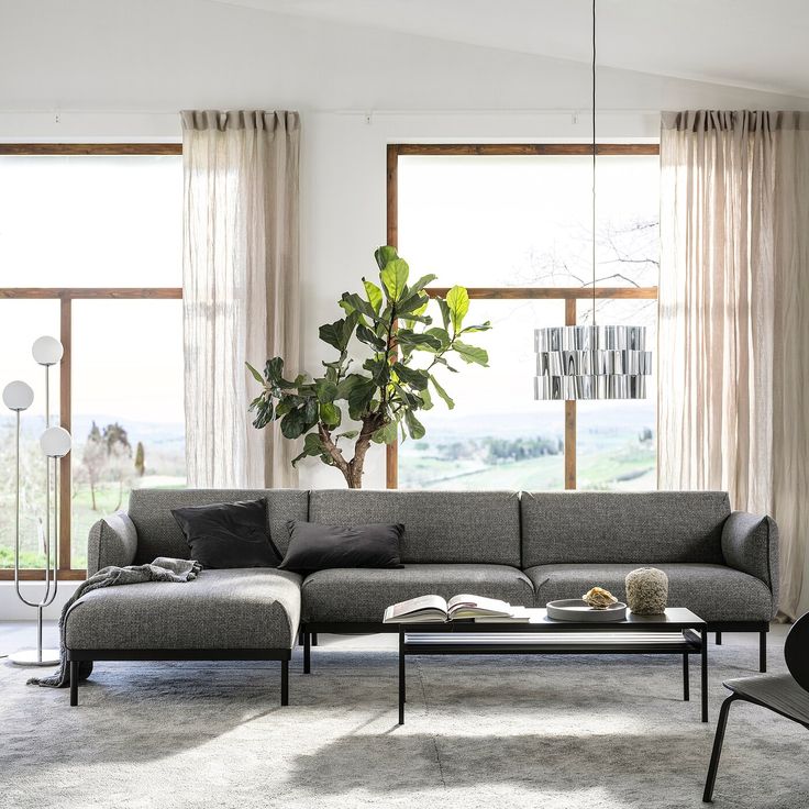 a modern living room with large windows and grey couches in front of the window