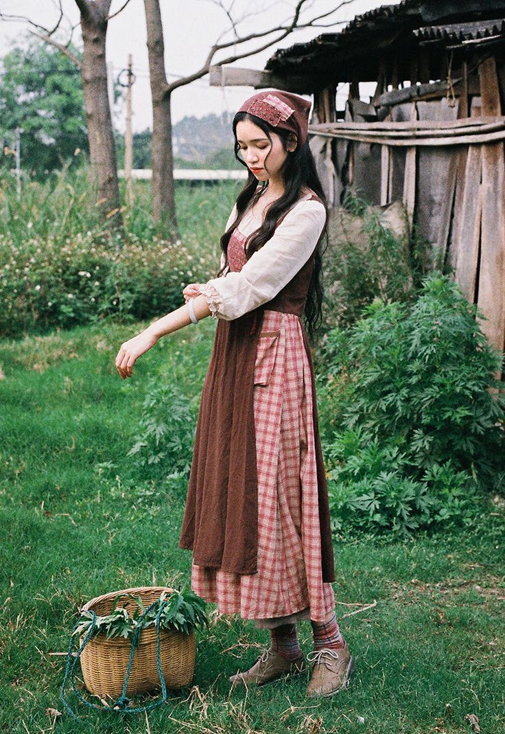 Early 19th century inspired village dress for everyday chores. This faux multi-layered dress features a white blouse part with a scoop neckline and three-quarter blouson sleeves, and a pinafore dress with plaid and ditsy floral patchwork layers. We've deliberately designed the floral patchwork to slant towards one side and attached it with an adjustable lace-up. There's a little pocket dangling at the waist to keep your phone or other knick-knacks. Full knit plaid skirt and partial linen brown s Pioneer Inspired Outfits, House Keeper Outfit, Layered Dresses Outfit, Puritan Outfit, Victorian Peasant Clothing, Villager Dress Vintage, Chores Outfit, Patchwork Dress Outfit, Cottagecore Prairie Dress For Gatherings