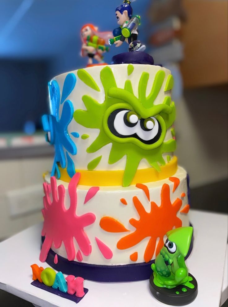 a cake decorated with splats and characters on it's sides is shown