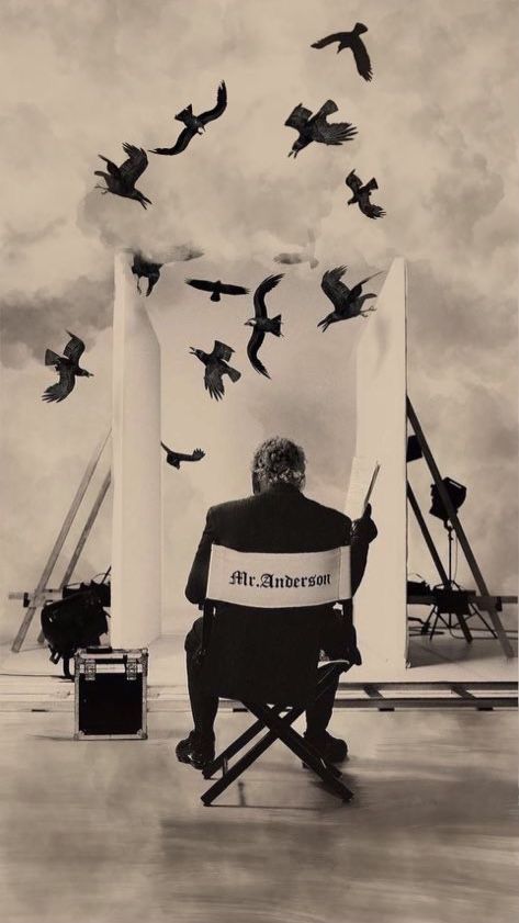 a man sitting in a chair with birds flying over him and writing on his paper