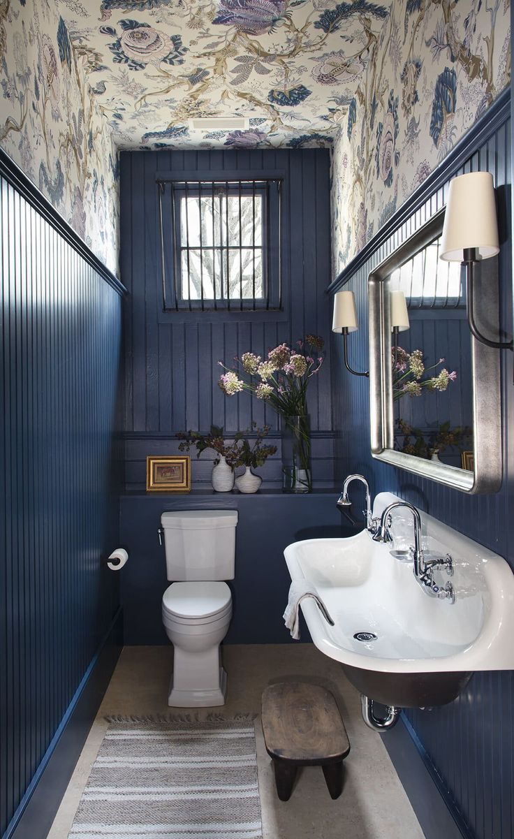 a bathroom with blue walls and floral wallpaper on the ceiling, along with a white toilet and sink