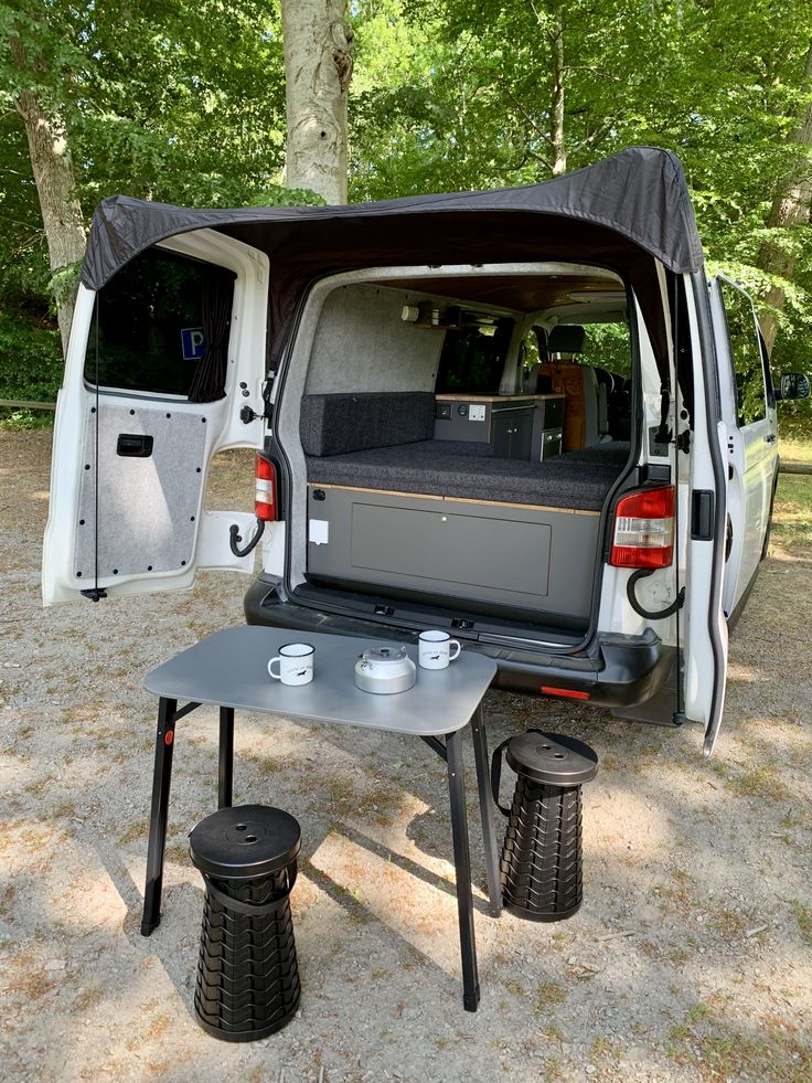 the back end of a van with its door open and two stools under it