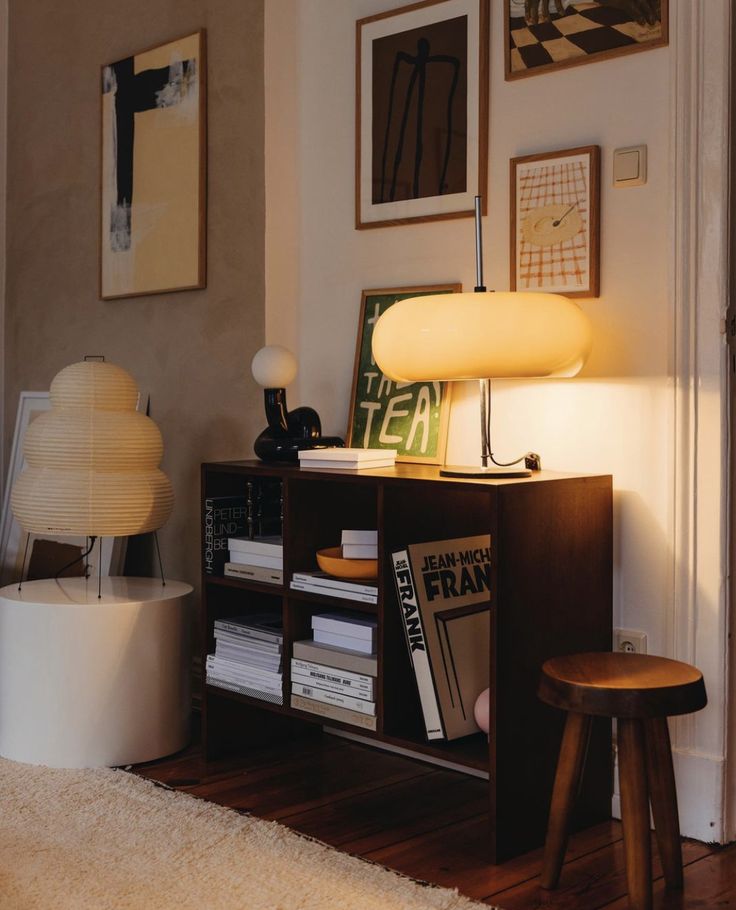 a living room filled with furniture and a lamp on top of a wooden table next to a book shelf