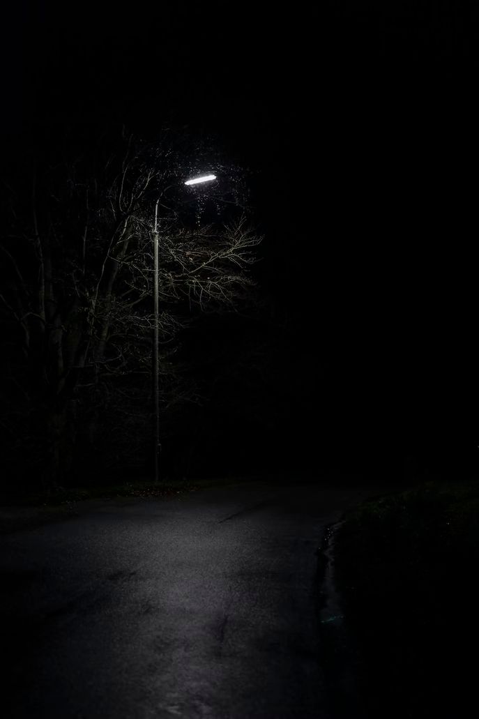 an empty street at night with the light turned on and no one is in it