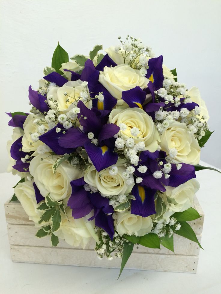 a bouquet of white and purple flowers in a wooden box with greenery on the side