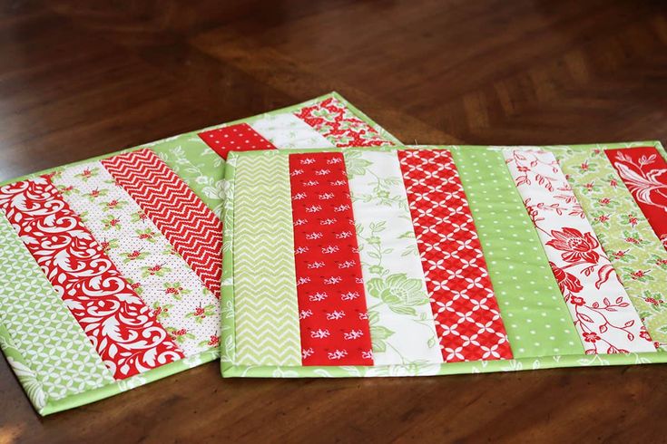 three quilted placemats sitting on top of a wooden table next to each other