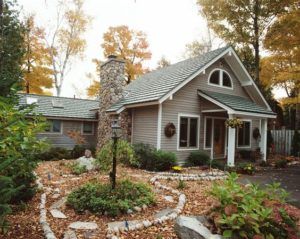 a house in the fall with leaves on the ground and rocks around it's base