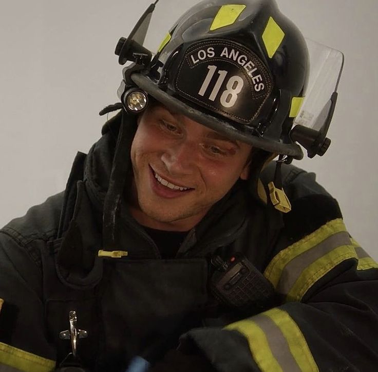 a smiling fireman wearing a black and yellow uniform