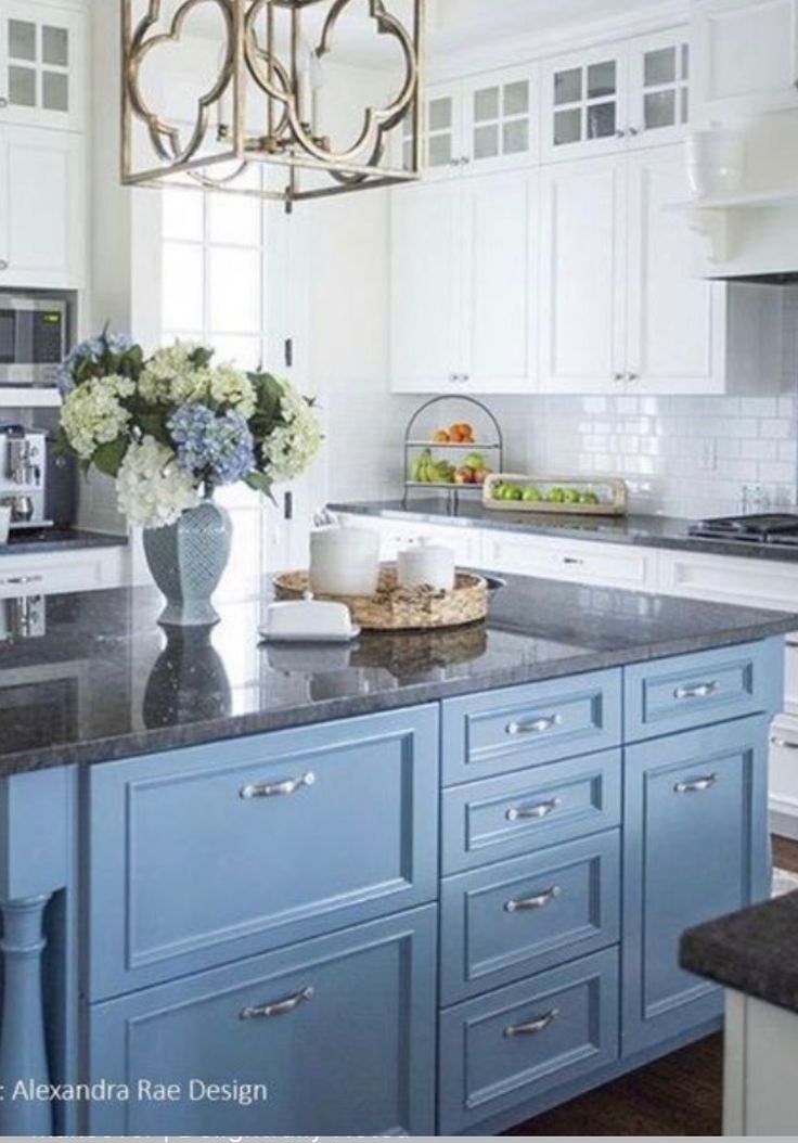 a kitchen with white cabinets and blue island