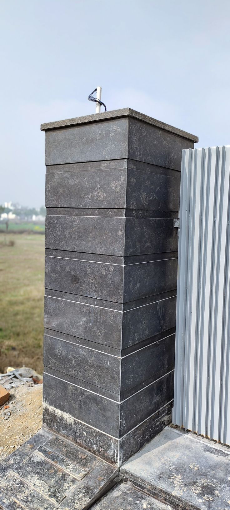 an outdoor toilet in front of a metal fence with a bird perched on it's top