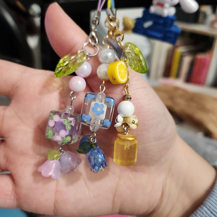 a person holding several different charms in their hand, including lemons and blueberries