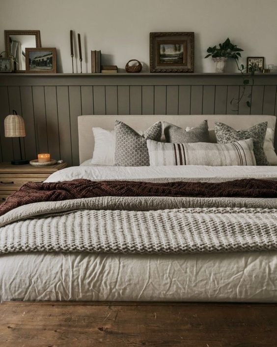 a bed with pillows and blankets on top of it in a bedroom next to a shelf