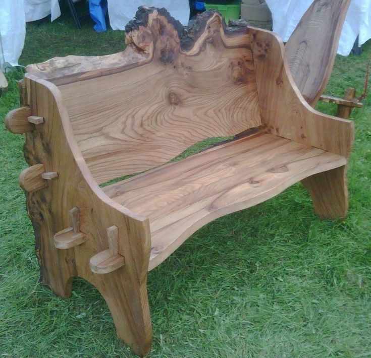 a wooden bench sitting on top of a green grass covered park field next to a white table cloth