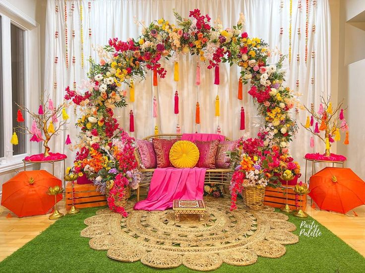 a decorated stage with pink and yellow flowers, orange umbrellas and other decorations on the floor