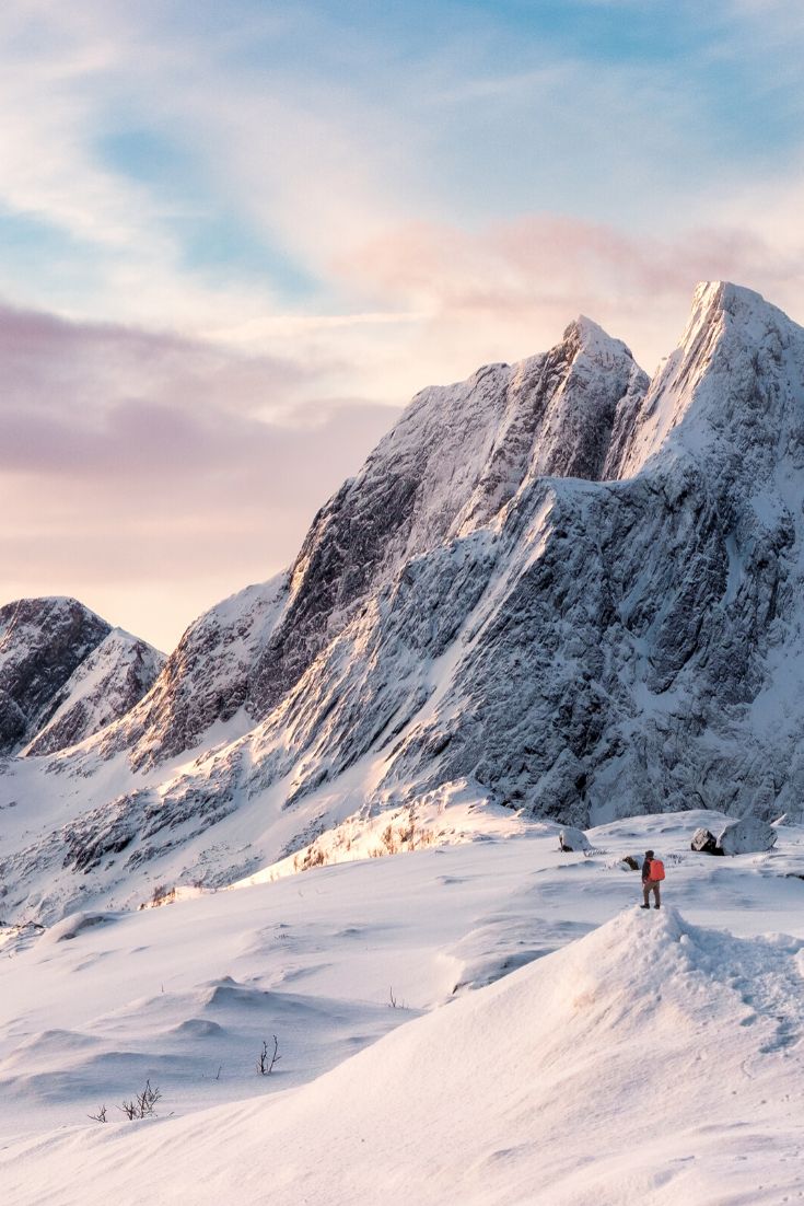 two people walking up the side of a snow covered mountain