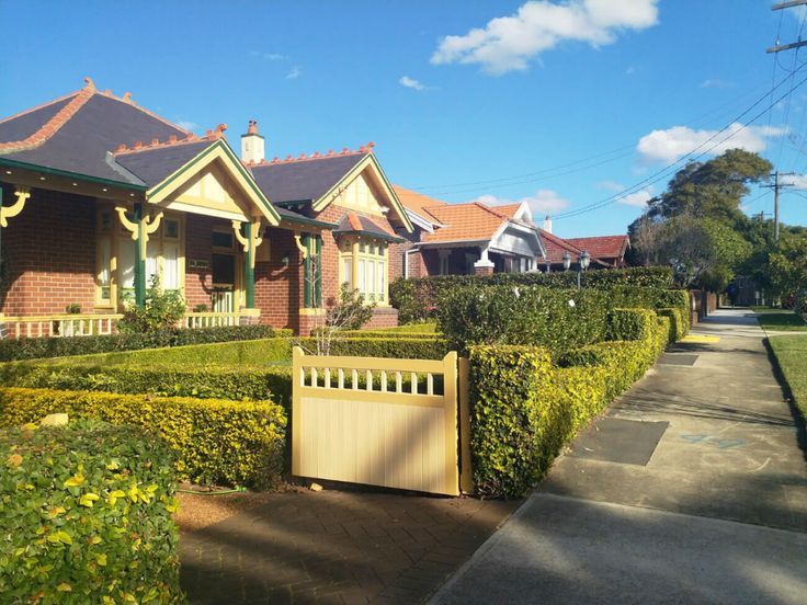 a row of houses with hedges in front of them and a driveway leading to the house