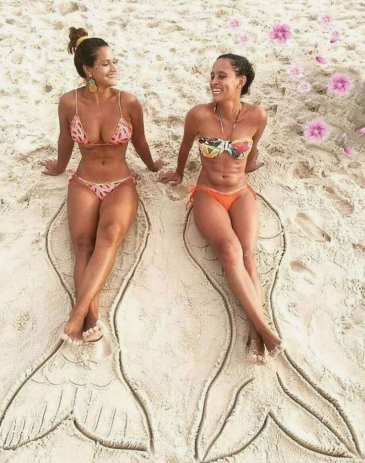 two women in bikinis sitting on the beach