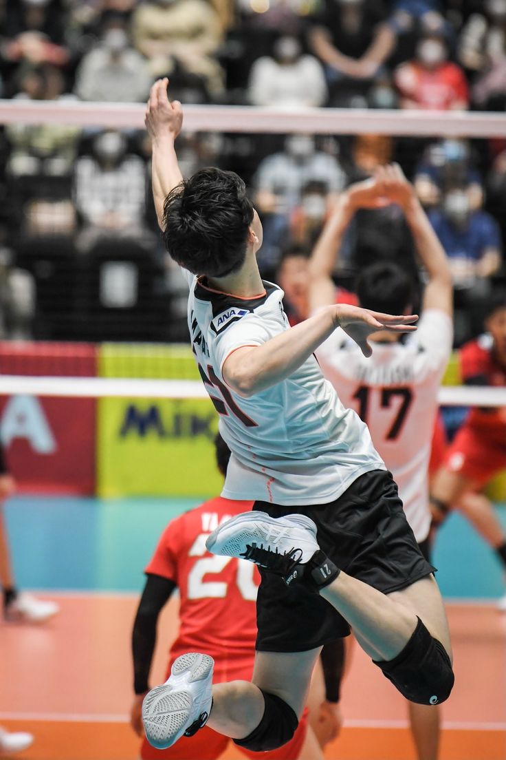 two men playing volleyball in front of an audience