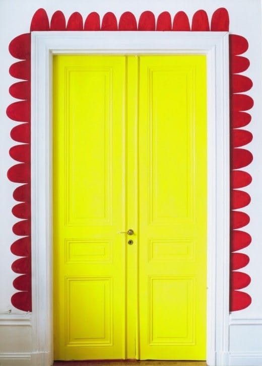 an open yellow door in front of a white wall with red circles on the walls