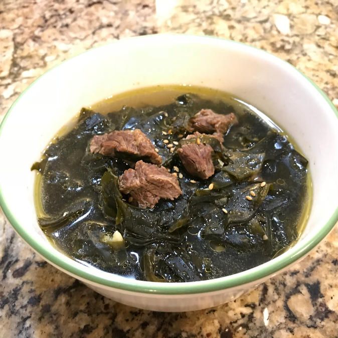 a white bowl filled with meat and greens