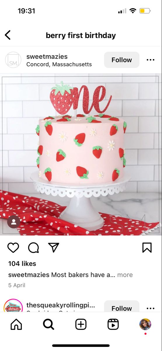 a pink cake sitting on top of a table next to a white brick wall and red polka dot ribbon