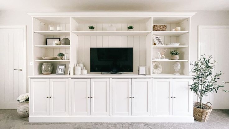 a living room with white cabinets and a flat screen tv on top of the entertainment center