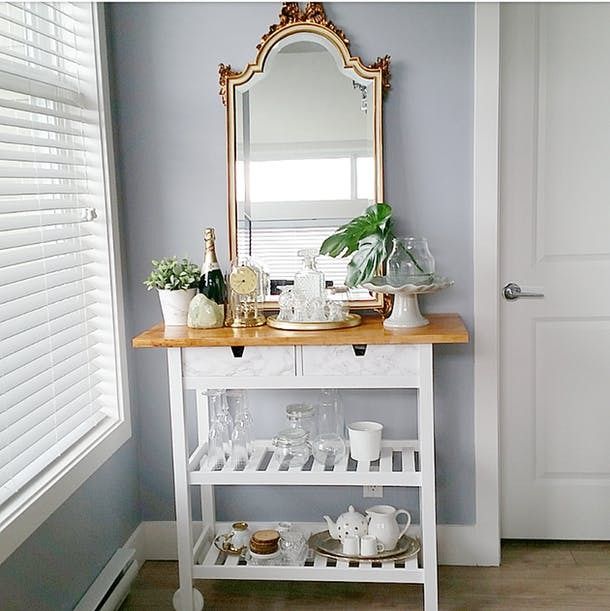 a white table with a mirror and dishes on it next to a door in a room