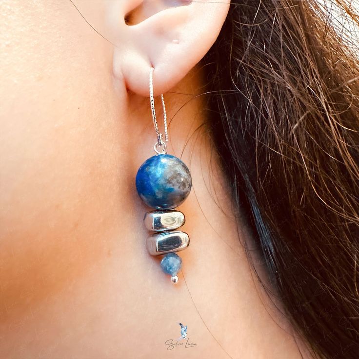 These elegant Lapis Lazuli bead stones dangle drop earrings feature a beautiful deep blue 12 mm Lapis Lazuli beads dangle drop and two painted silver Hematite stone beads, a faceted blue Kyanite tiny bead drop at the end. The beads are on solid 925 sterling silver eye pin, hooked on a diamond cut texture 925 sterling silver ear wire. Add these elegant Lapis Lazuli, Hematite and Kyanite beads dangle drop earrings to your everyday fine jewelry collection or as a gift for your loved one. Materials: 925 sterling silver, Lapis Lazuli, UV hematite, kyaniteDimensions: 1.84 x 0.46 in Jewelry Care: See more information about how to care for your jewelry here. Shipping Policy: Orders will be shipped within 1-3 business days. Economy shipping will take 7-14 days to arrive and standard shipping is 1- Silver Jewelry With Faceted Beads Made Of Lapis Lazuli, Silver Beaded Earrings With Natural Stones, Silver Jewelry With Faceted Beads In Lapis Lazuli, Elegant Adjustable Beaded Earrings With Gemstone Beads, Blue Drop Earrings With Dangling Beads, Elegant Earrings With Gemstone Beads, Adjustable Gemstone Bead Drop Earrings, Blue Gemstone Beads Earrings For Gift, Adjustable Drop Earrings With Gemstone Beads