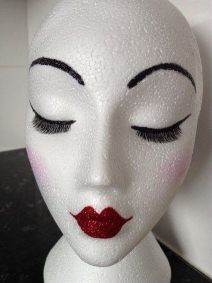 a white mannequin head with red lipstick on it's face and eyes