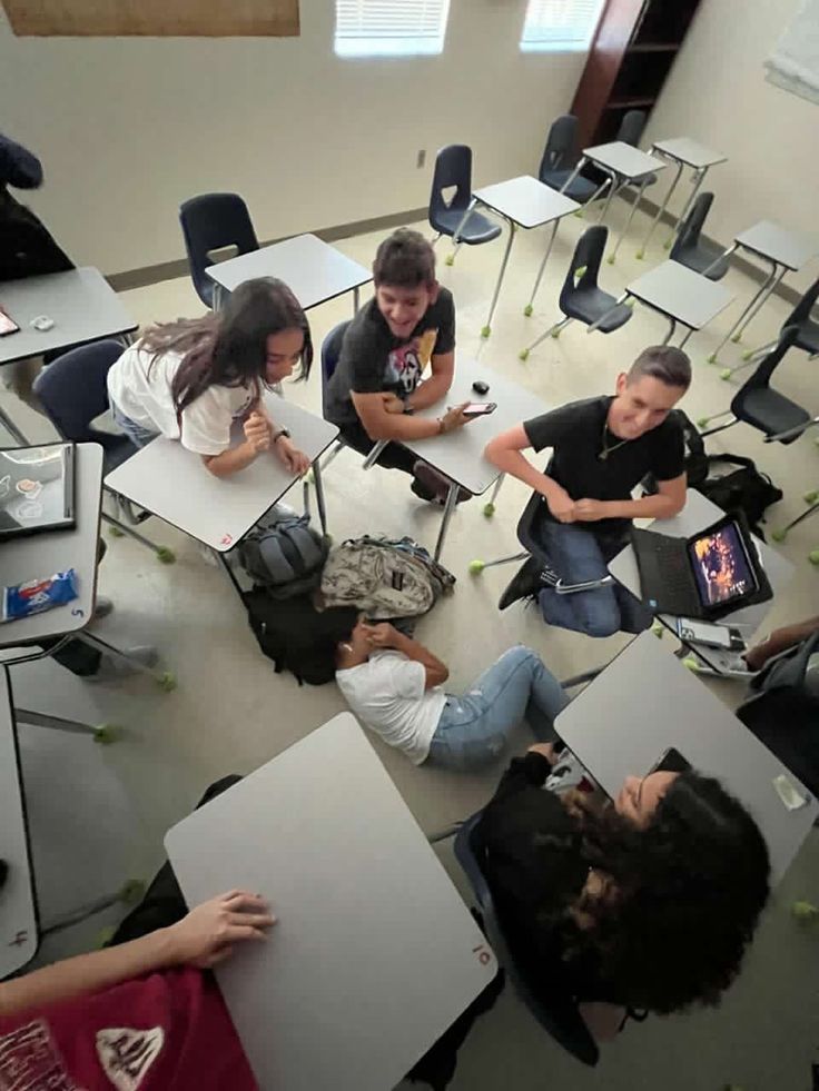 a group of people sitting around each other in a room with laptops on the floor