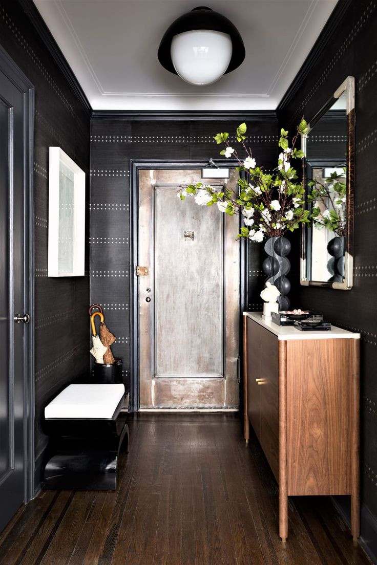 the hallway is decorated in black and white with wood flooring, an entry door, and a wooden cabinet