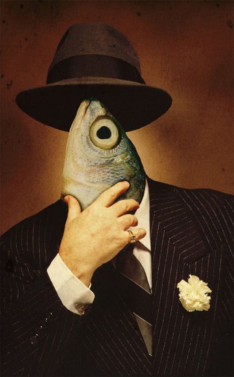 a man in a suit and hat holding a fish mask