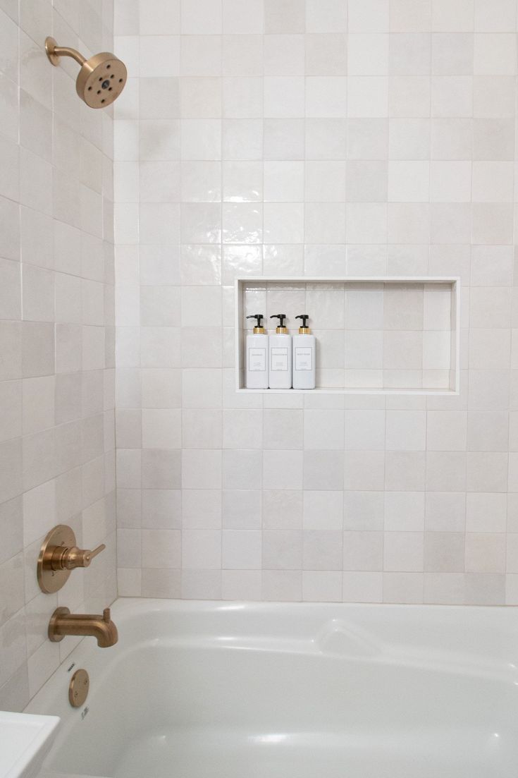 a bathtub with three soap dispensers on the wall