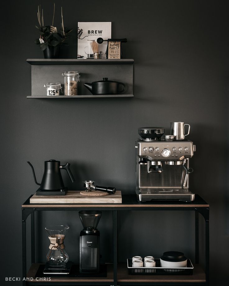 a coffee maker and some cups on a shelf in a room with two shelves above it